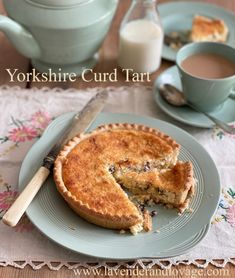 a piece of pie on a plate next to a cup of coffee and a teapot