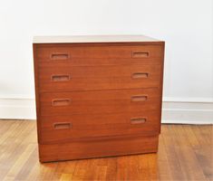 a wooden dresser sitting on top of a hard wood floor next to a white wall