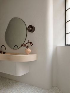 a bathroom with a sink, mirror and vase on the counter in front of it