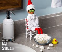 an elf sitting in a chair next to a bowl of marshmallows