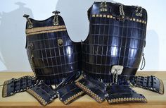 two pieces of armor sitting on top of a wooden table