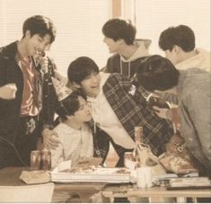 a group of young men standing around a table