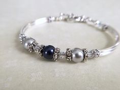 This subtle and delicate looking bangle bracelet is made with one midnight blue and two silver Swarovski Crystal pearls joined with sterling silver star bead caps that separate the 4mm Swarovski Crystal AB bicones. Sterling silver plated curved tube beads and a sweet heart toggle completes this comfortable bangle bracelet. Pictures are nice but by no means do justice to the actual piece! This is truly a rich and classy looking bracelet. * Matching earrings https://www.etsy.com/listing/461992687/ Classic Silver Pearl Bracelet For Bridesmaids, Nickel Free Round Beads Bracelet For Wedding, Nickel Free Wedding Bracelet With Round Beads, Silver Round Jewelry For Mother Of The Bride, Silver Bracelets For Formal Mother's Day Occasion, Silver Bracelets For Formal Occasions On Mother's Day, Sterling Silver Bracelet For Bridesmaids, Silver Bracelets For Mother's Day Formal Occasion, Silver Bracelets For Formal Wear On Mother's Day