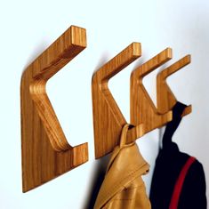 the coat rack is made out of wood and has three hooks on each side that hold coats