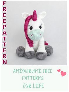 a crocheted stuffed unicorn with pink mane sitting on top of it's legs