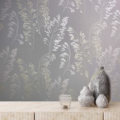 a vase and some white flowers on a table next to a wallpapered wall