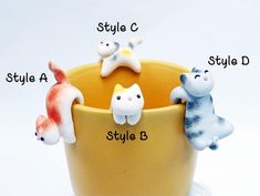 four ceramic cats sitting in a yellow cup with names on the front and side, including style a, style b, style c