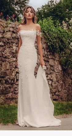 a woman in a white wedding dress standing on the street with her arms around her waist