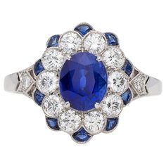 A beautiful update on the classic Lady Diana ring, this platinum Art Deco inspired ring centers an oval-shaped sapphire weighing approximately 1.65 carats, with well saturated, deep blue color, surrounded by sparkling round brilliant-cut diamonds and calibre-cut sapphires. The sapphire weigh totals 2.05 carats, and the diamond weight is 0.71ct. Elegant, eye-catching and exceptionally well made. Classic Luxury Sapphire Ring With Diamond Cut, Luxury Classic Sapphire Ring With Intricate Design, Luxury Fine Jewelry Sapphire Ring With Diamond Cut, Luxury Heirloom Sterling Silver Sapphire Ring, Luxury Intricate Design Sapphire Ring, Luxury Art Deco Sapphire Ring With Single Cut Diamonds, Luxury Art Deco Sapphire Ring With Round Cut, Blue Sapphire Wedding Ring 1stdibs, Luxury Art Deco Sapphire Ring In Platinum