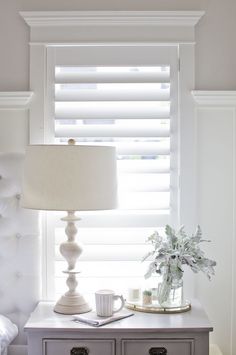 a white lamp sitting on top of a table next to a vase filled with flowers