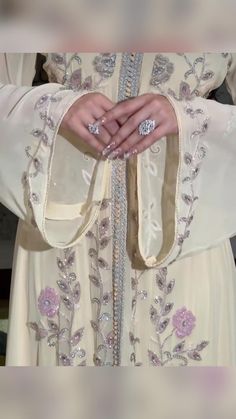 a close up of a person's hands with rings on their fingers and dress