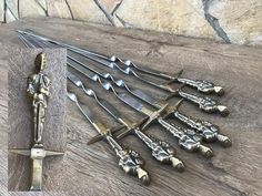 several different types of knives and forks on a wooden table next to a stone wall