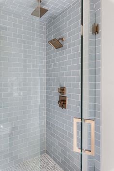 a shower with blue tile and gold fixtures