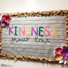 a sign that says kindness grows love with paper flowers on the front and bottom of it