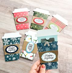 someone holding up some christmas cards on top of a wooden table with snowflakes