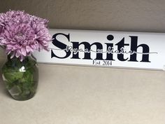 a vase filled with purple flowers sitting next to a sign that says smith est 2014