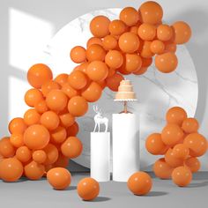 an orange cake surrounded by balloons in front of a white wall with a deer on it