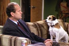 a man sitting on top of a couch next to a dog in front of him