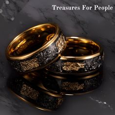 two gold wedding rings with black and white marble in the middle, sitting on top of each other