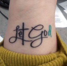 a tattoo that says let go on the wrist and is black with green lettering in cursive font