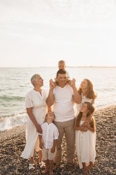 a family standing on the beach with their arms around each other