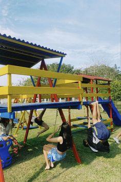 two children playing on a colorful playground set in the grass with their arms and legs up