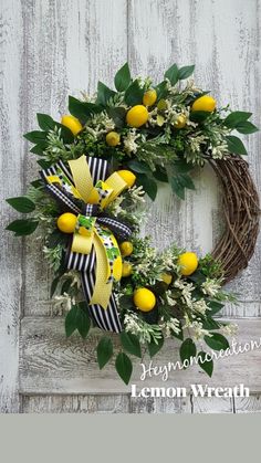 a wreath with lemons and greenery hanging on a white wooden wall next to a door