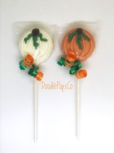 two pumpkin shaped lollipops in plastic wrappers