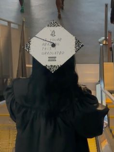 a woman with a graduation cap on her head is walking down an escalator