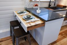 a kitchen table with two plates on it and three stools in front of it