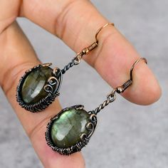 Radiant Elegance Awaits Elevate your style with our stunning Labradorite Copper Gemstone Earrings. Each pair is meticulously handmade, featuring genuine Labradorite stones intricately wrapped in copper wire for a unique and elegant look. These designer dangle earrings exude sophistication and charm, adding a touch of bohemian flair to any outfit. Cabochon Earrings, Wire Wrapping Stones, Wire Wrapped Earrings, Wrapped Jewelry, Labradorite Stone, Beads And Wire, Wire Wrap, Stone Earrings, Wire Wrapped Jewelry