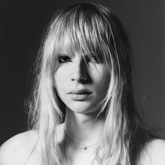 a black and white photo of a woman with long blonde hair, wearing a necklace