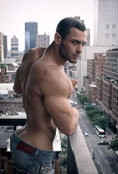 a shirtless man standing on top of a balcony holding a wine glass in his hand