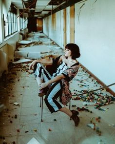 a woman sitting on a chair in an empty building with confetti all over the floor