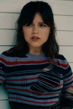 a woman standing in front of a white wall with her hands on her hips and looking at the camera