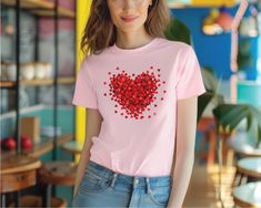 a woman wearing a pink t - shirt with red hearts on it