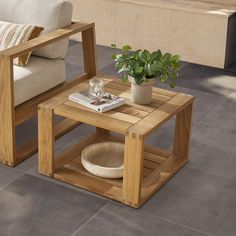 a wooden table sitting on top of a cement floor next to a chair and couch