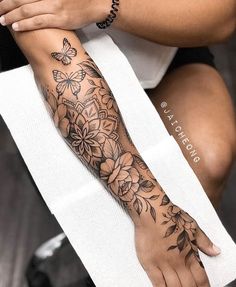 a woman's arm with flowers and butterflies on it