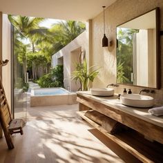 a bathroom with two sinks and a bathtub next to a large window that has palm trees in it