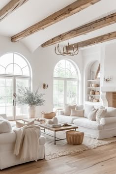 a living room filled with white furniture and large arched windows in front of two tall windows