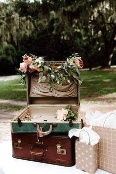 an open suitcase sitting on top of a table next to two boxes filled with flowers