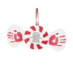 two handprints are hanging from a red and white ornament