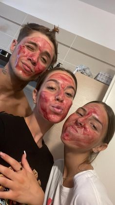 three people with their faces covered in red and pink makeup are posing for the camera