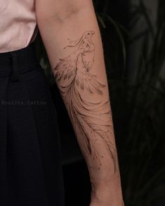 a woman's arm with a tattoo on it and a bird in the background