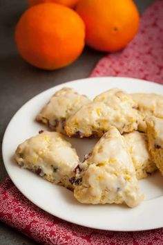 oranges and cookies are sitting on a white plate next to some red napkins