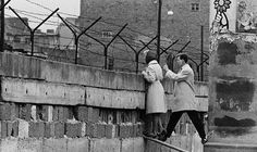 an old photo of two people standing on the edge of a wall with barbed wire