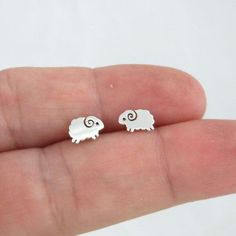 A sweet and tiny pair of Sheep studs in sterling silver.Earrings are made of 925 silver and size 6mm x 5mm.The earrings have been polished to a mirror shine.They earrings are great for those with sensitive ears.Mix and match with my other stud earringsIncludes sterling silver earring backs.This listing is for one pair (2 pieces). Funky Stud Earrings, Earrings Animals, Sheep Earrings, Earrings Kids, Black Heart Earrings, Aries Ram, Dinosaur Earrings, Cute Stud Earrings, Baby Earrings