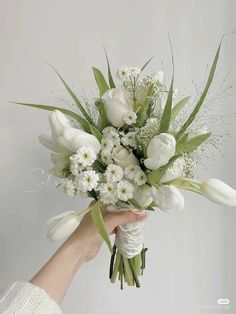 a woman holding a bouquet of white flowers