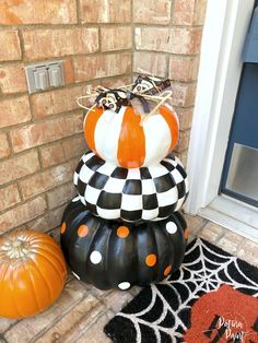 three pumpkins stacked on top of each other in front of a brick wall and door