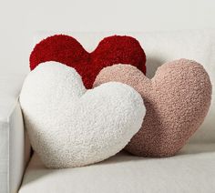 two heart shaped pillows sitting on top of a white couch